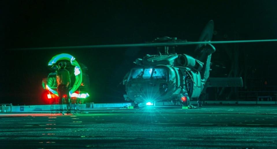 An aviation boatswain's mate signals signals to a helicopter the flight deck of an ESB