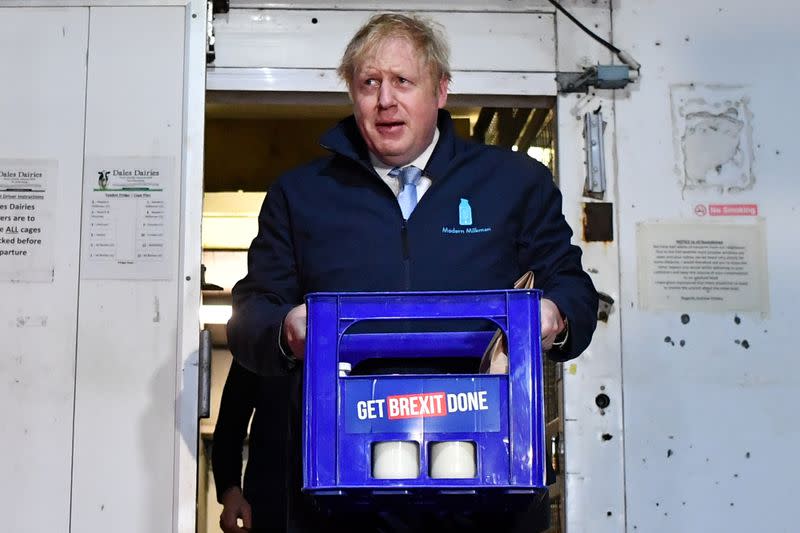 Britain's Prime Minister Boris Johnson carries a crate of milk to deliver to customers in Guiseley, Leeds