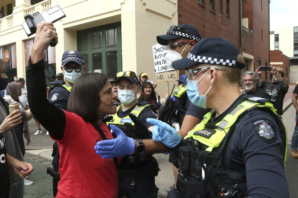 A refugee protester is surrounded by police outside the Park Hotel in Melbourne, Australia, Saturday, Jan. 8, 2022. The world’s No. 1-ranked tennis player Novak Djokovic is also being held there after border officials canceled his visa last week over a vaccine requirement.(AP Photo/Hamish Blair)
