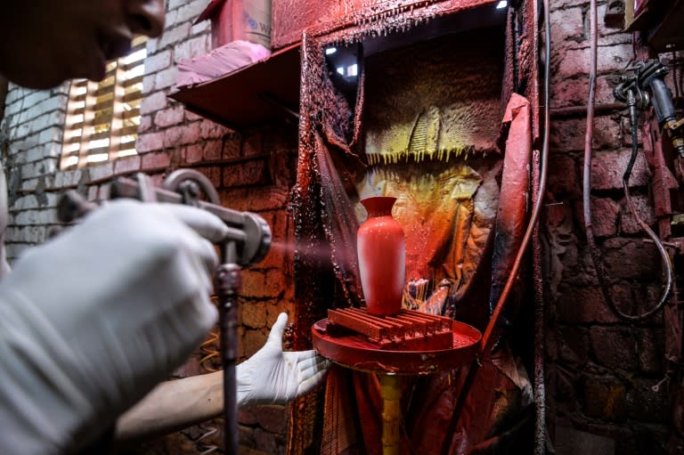 One of Mostafa el-Agoury's employees spray-paints a vase at his pottery workshop on June 21, 2018