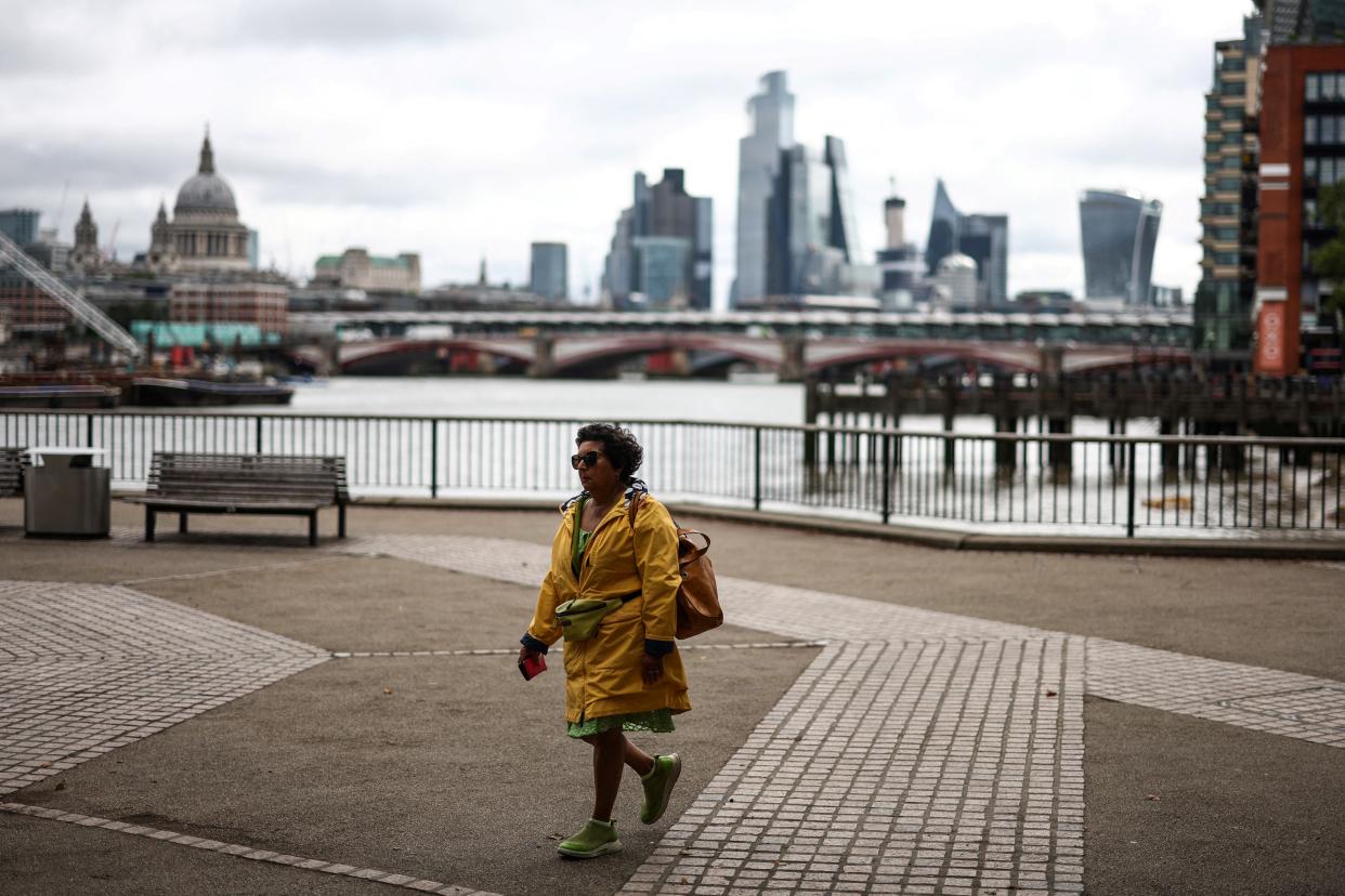 A pedestrian, wearing a rain jacket, walks on the Southbank by the River Thames, in central London, on July 27, 2023 on a gloomy summer day. (Photo by HENRY NICHOLLS / AFP) (Photo by HENRY NICHOLLS/AFP via Getty Images)