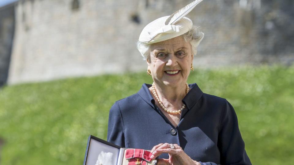 Angela Lansbury poses with her Dame Commander (DBE) medal given to her by Queen Elizabeth II at an Investiture ceremony at Windsor Castle on April 15, 2014 in Berkshire, England.