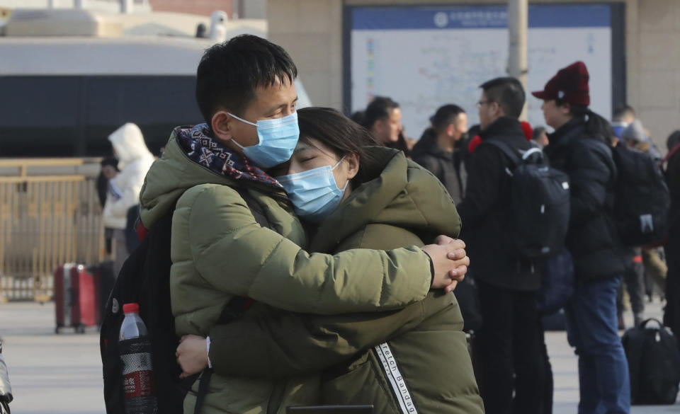 A couple wearing masks hug in front of Beijing Station in Beijing, China on January 22, 2020, prior to China's Lunar New Year holiday. Source: The Yomiuri Shimbun via AP Images 