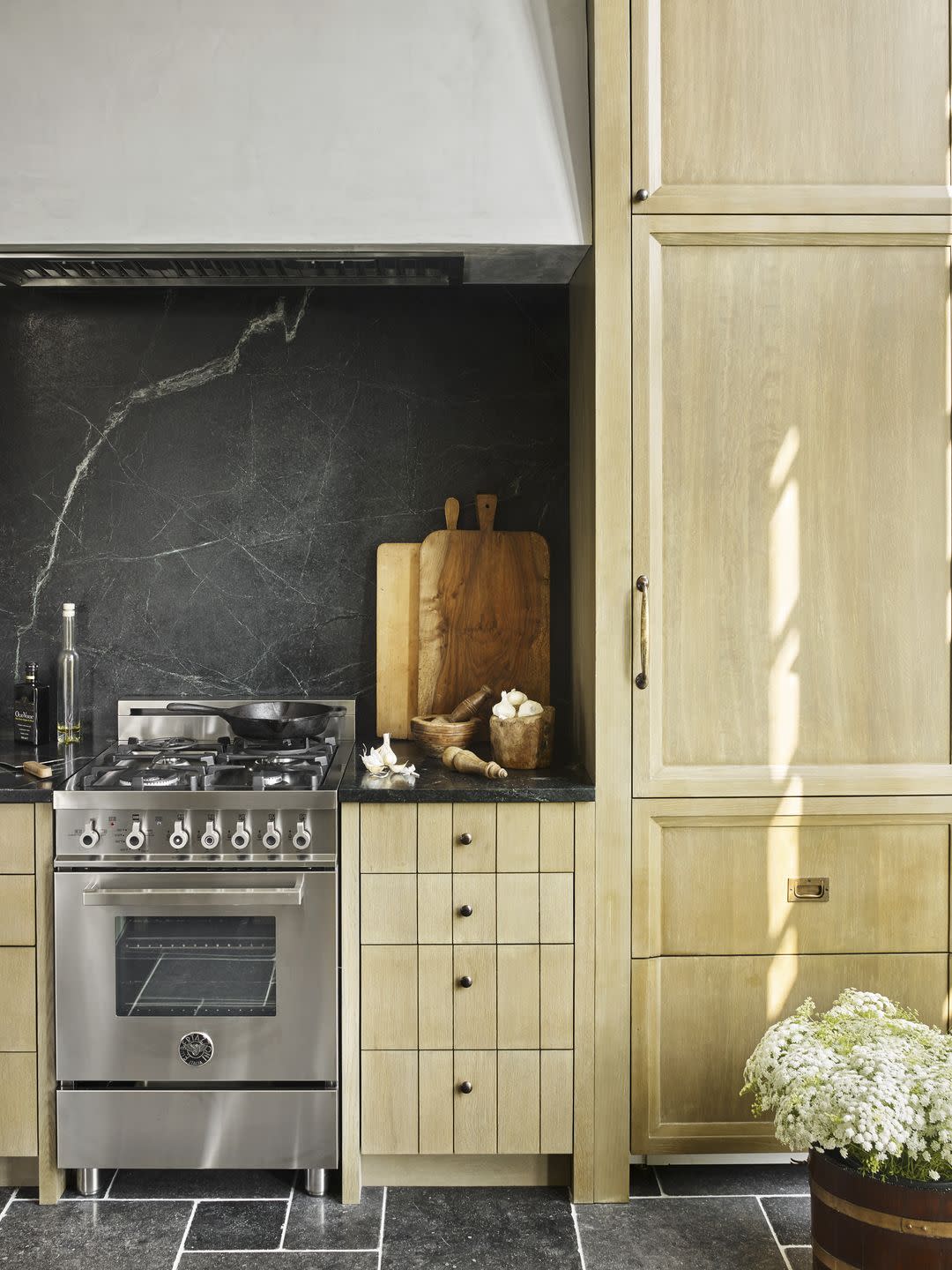 a galley kitchen with warm wood grain cabinets and a stainless steel range