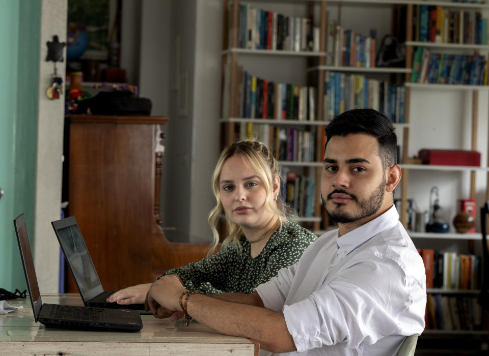 Leonardo de Carvalho Leal, right, and Mayara Stelle, who administer the Twitter account Sleeping Giants Brazil, use their computers in Sao Paulo, Brazil, Friday, Dec. 11, 2020. Sleeping Giants is a platform for activism whose stated mission is to attack the financing of hate speech and dissemination of fake news. (AP Photo/Andre Penner)