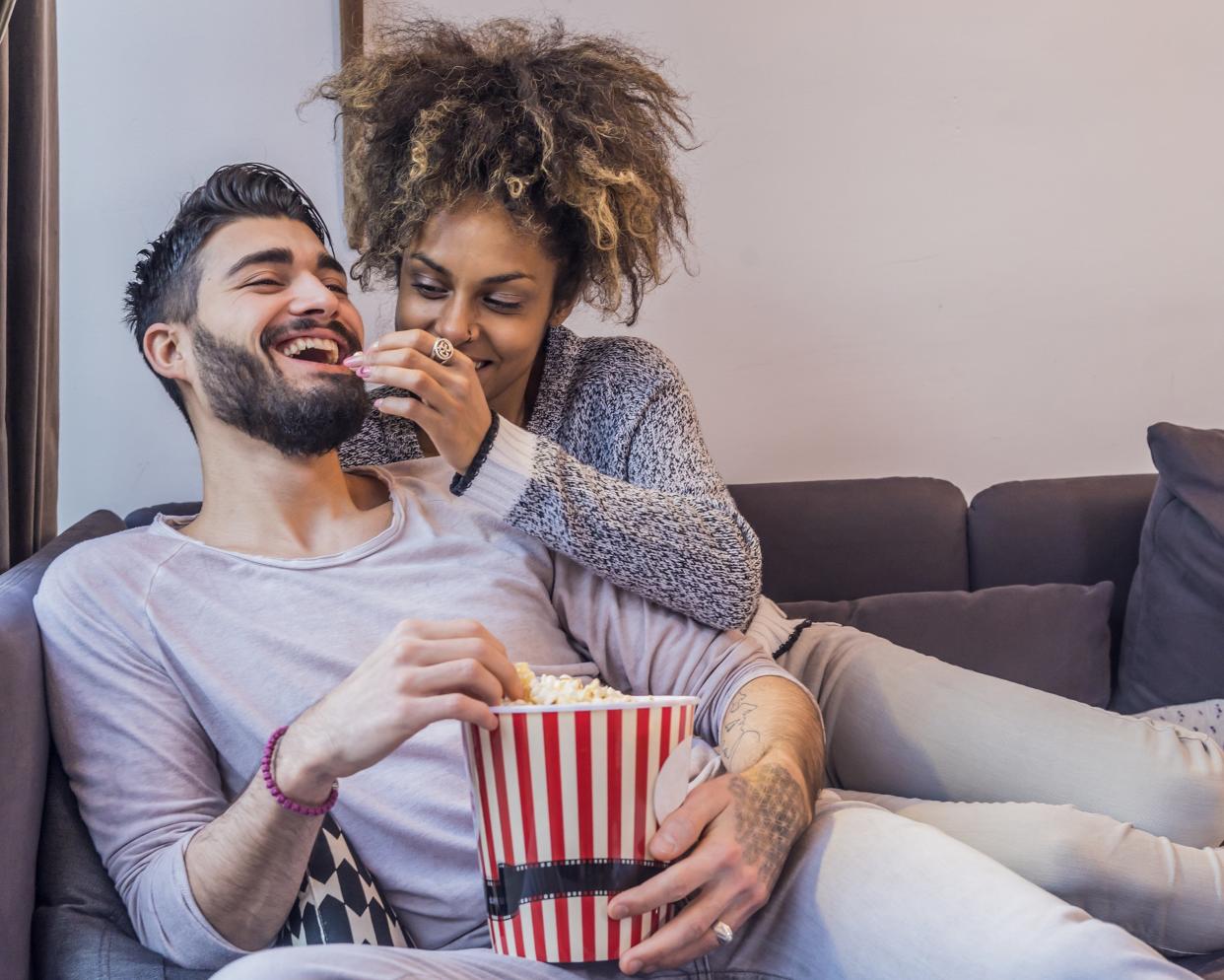 couple on couch eating popcorn and watching movie