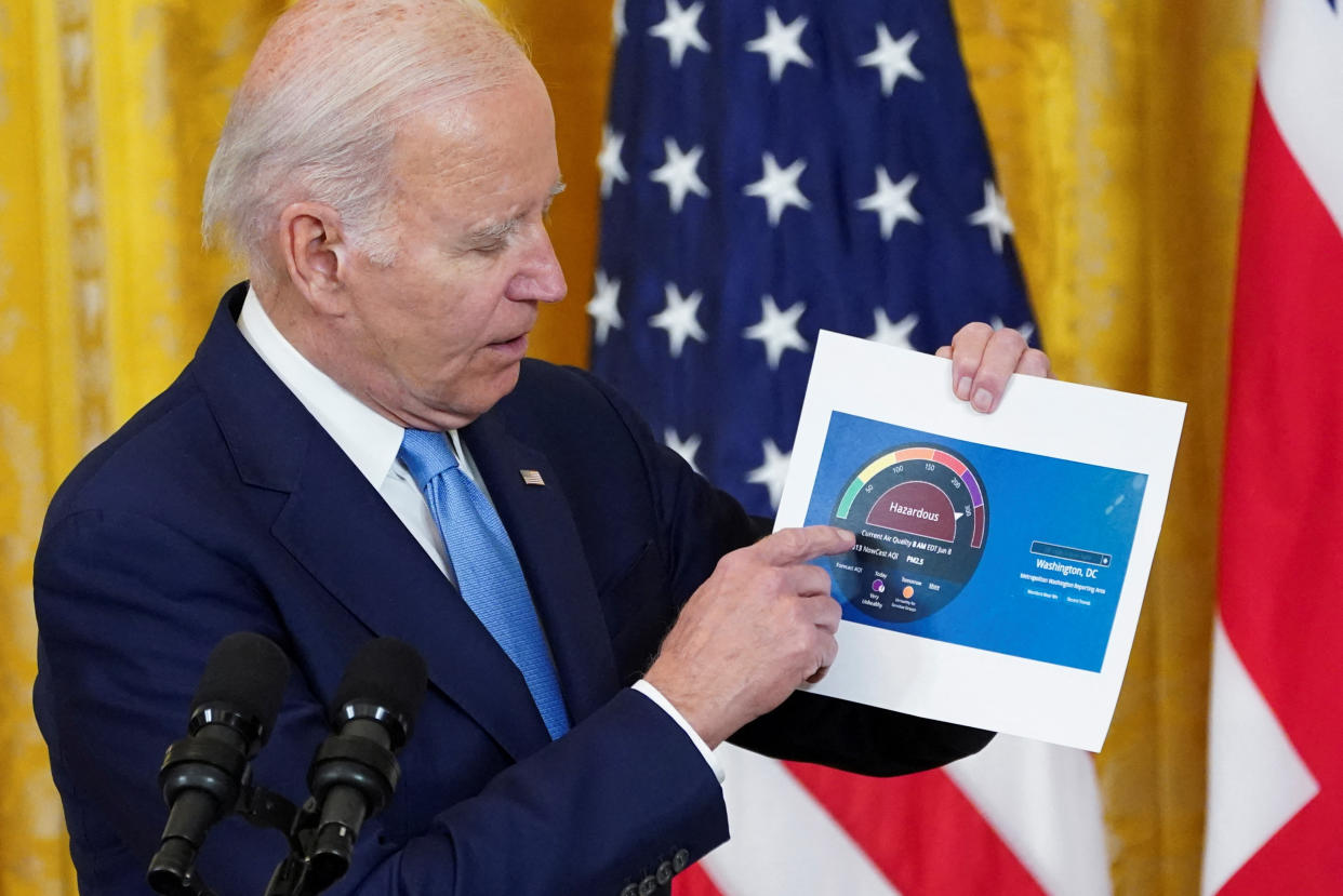President Biden displays a printout of the U.S. Air Quality Index for Washington, D.C., at the White House on Thursday. (Kevin Lamarque/Pool via Reuters).