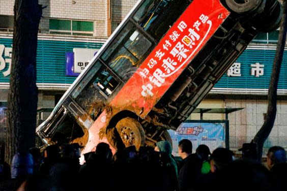 Chinese rescuers watch on as the bus is lifted out of the sinkhole (AFP via Getty Images)