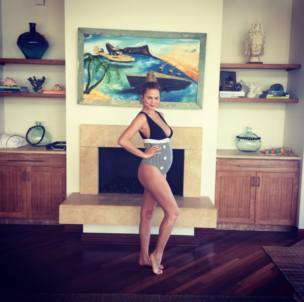 Chrissy Teigen wears a striped one-piece bathing suit on vacation during the holidays.