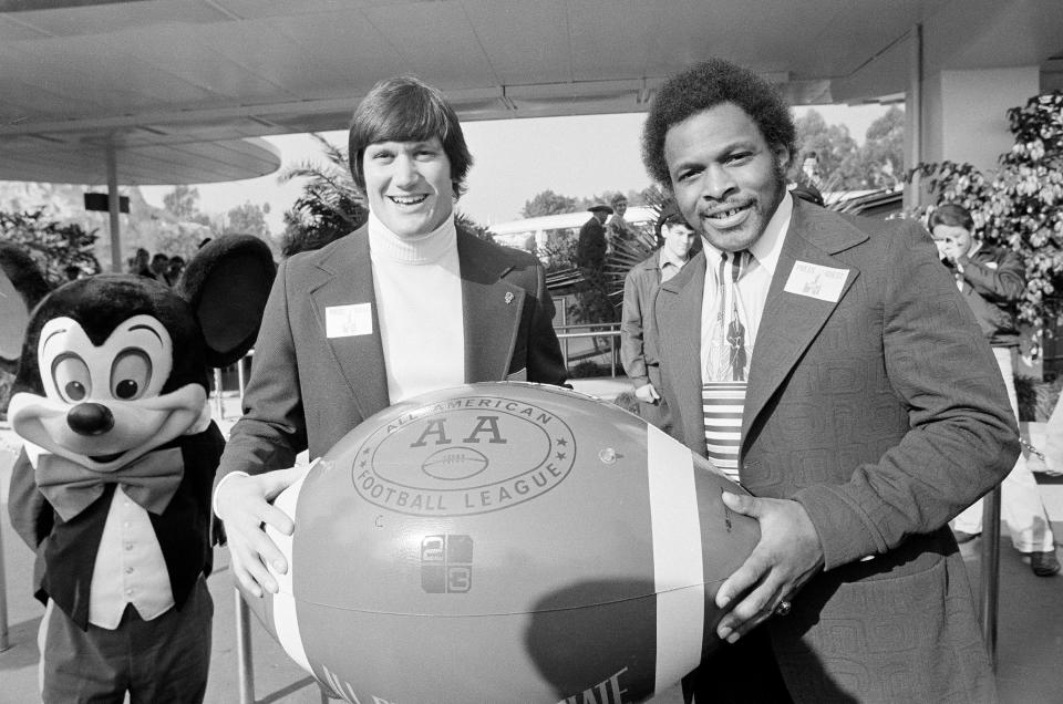 John Sciarra, left, of UCLA, and Archie Griffin of Ohio State pose with an "All American" football as the two Rose Bowl-bound teams visited Disneyland in Anaheim, Calif., Dec. 22, 1975.  (AP Photo/Wally Fong)