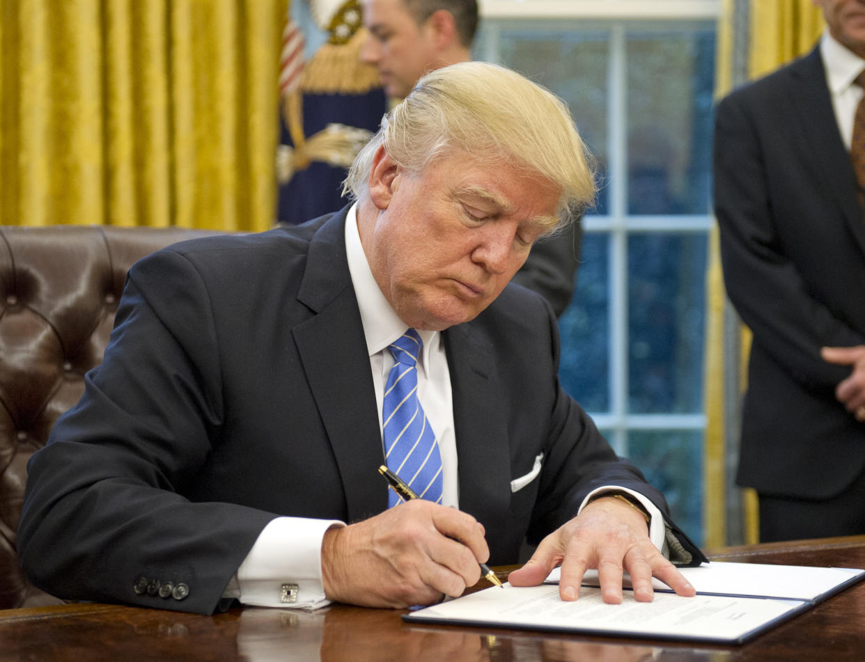 WASHINGTON, DC - JANUARY 23:  (AFP OUT) U.S. President Donald Trump signs the last of three Executive Orders in the Oval Office of the White House in Washington, DC on Monday, January 23, 2017.  These concerned the withdrawal of the United States from the Trans-Pacific Partnership (TPP), a US Government hiring freeze for all departments but the military, and 
