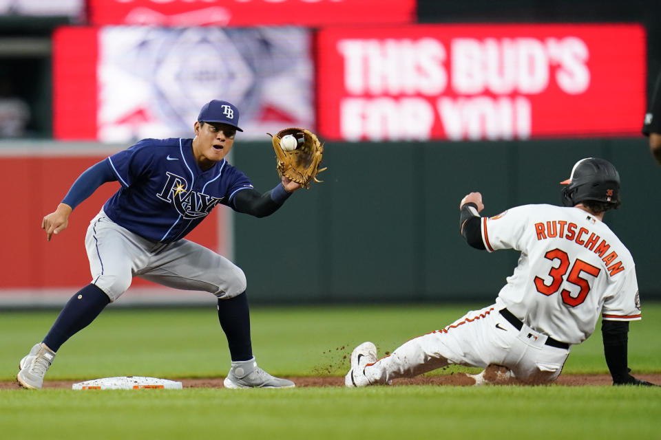 Tampa Bay Rays shortstop Yu Chang, left, makes a catch before tagging out Baltimore Orioles' Adley Rutschman (35) trying to move to second base on a pitch that bounced off Rays catcher Christian Bethancourt during the second inning of a baseball game, Tuesday, July 26, 2022, in Baltimore. (AP Photo/Julio Cortez)