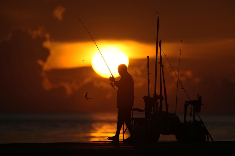 FILE - A fisherman reels in his catch as the sun rises over the Atlantic Ocean, June 28, 2023, in Bal Harbour, Fla. An already warming Earth steamed to its hottest June on record, with global oceans setting temperature records for the third straight month, the U.S. National Oceanic and Atmospheric Administration announced Thursday, July 13. (AP Photo/Wilfredo Lee, File)