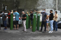 Family members of patients hospitalized with COVID-19 line up with empty oxygen tanks in an attempt to refill them, outside the Nitron da Amazonia company, in Manaus, Amazonas state, Brazil, Friday, Jan. 15, 2021. Doctors in the Amazon rainforest’s biggest city are having to choose which COVID-19 patients can breathe amid dwindling oxygen stocks and an effort to airlift some of the infected to other states. (AP Photo/Edmar Barros)