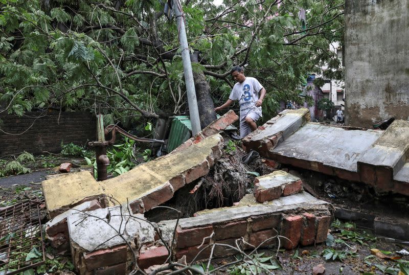 A man walks over a collapsed wall after Cyclone Amphan made its landfall in Kolkata