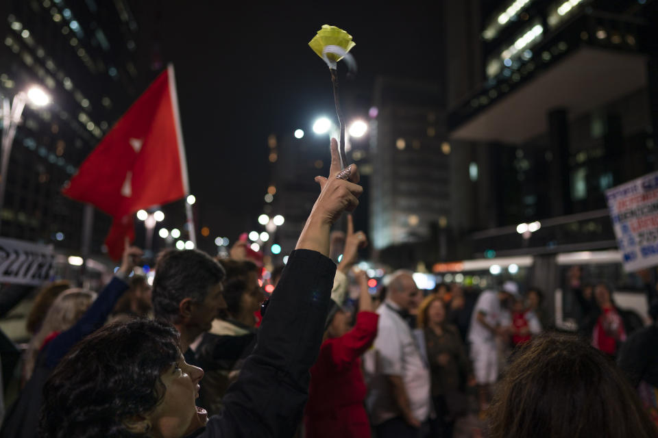 A demonstrator lifts a paper flower during a march in support of journalist Glenn Greenwald in Sao Paulo, Brazil, Tuesday, July 30, 2019. Brazil's president has raised the possibility of jail for Greenwald a few days after members of his party said the American's Brazil-based internet publication was "aligned with criminal hackers" for reporting on hacked phone calls. (AP Photo/Victor R. Caivano)