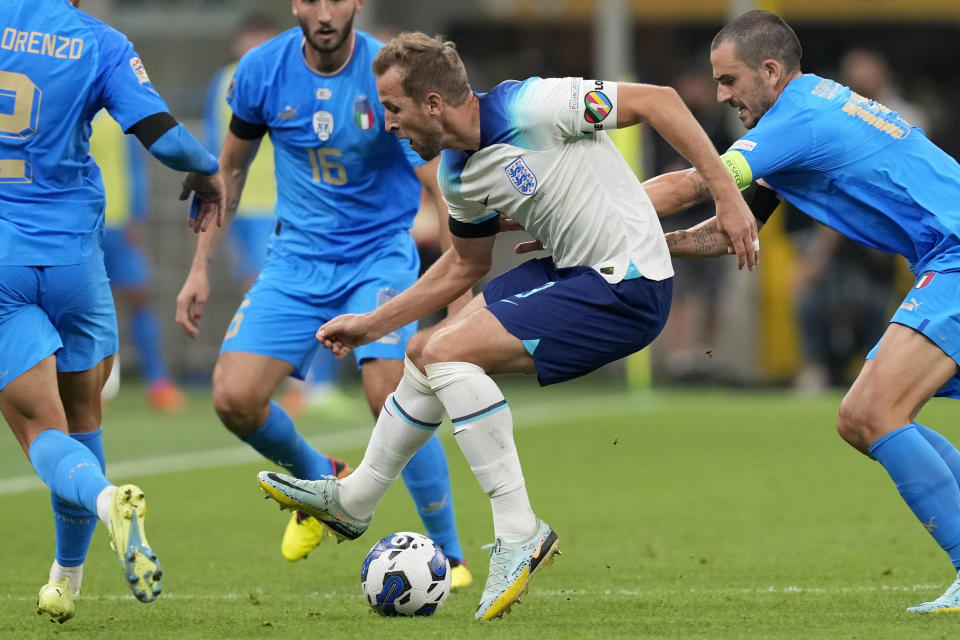 FILE - England's Harry Kane, center, wearing a rainbow armband, controls the ball during the UEFA Nations League soccer match between Italy and England at the San Siro stadium, in Milan, Italy, on Sept. 23, 2022. The captains of seven European nations will not wear anti-discrimination armbands in World Cup games after threats from FIFA to show yellow cards to the players. The seven soccer federations say "we can’t put our players in a position where they could face sporting sanctions.” (AP Photo/Antonio Calanni, File)