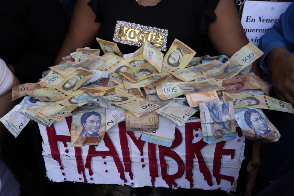 ARCHIVO - Un manifestante lleva una caja con la palabra "hambre" escrita en rojo y un montón de billetes de bolívares, en una protesta para reclamar mayores salarios y beneficios en Caracas, Venezuela, el 11 de enero de 2023. (AP Foto/Ariana Cubillos, Archivo)