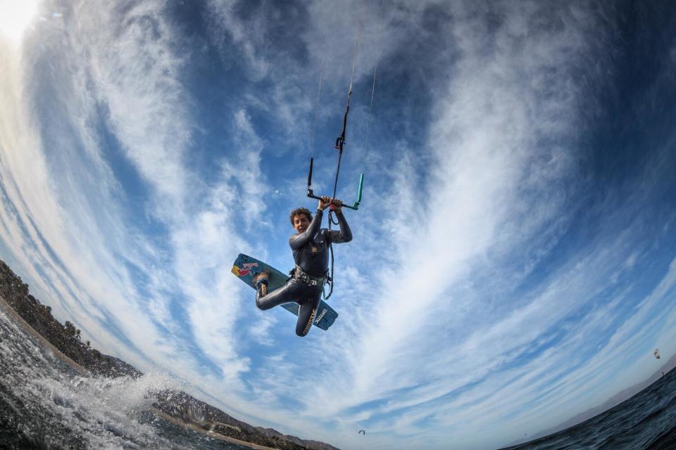 A kite surfer launches off a wave