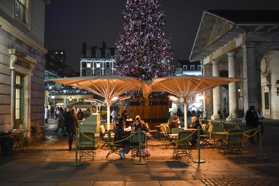 People eat outside in Covent Garden market, as non-essential shops are allowed to reopen after England's second lockdown ended in London, Wednesday, Dec. 2, 2020. Pfizer and BioNTech say they've won permission Wednesday for emergency use of their COVID-19 vaccine in Britain, the world's first coronavirus shot that's backed by rigorous science -- and a major step toward eventually ending the pandemic.(AP Photo/Alberto Pezzali)