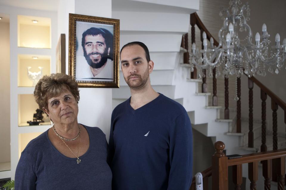 In this Sunday, April 6, 2014 photo, Itsik Mizrahi and his mother Mazal pose in from of a portrait of his brother Haim, who was killed in 1993 by a group Palestinians, at their home in Rishon Lezion, Israel. Palestinian Esmat Mansour was sentenced to 22 years in prison for taking part in the murder and was released in August 2013. (AP Photo/Dan Balilty)