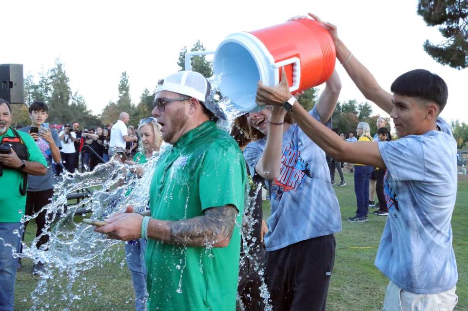 A Highland High (Bakersfield) coach gets doused with water in celebration of the girls team winning the Division II title at the CIF Central Section cross country championships at Woodward Park on Nov. 16, 2023.