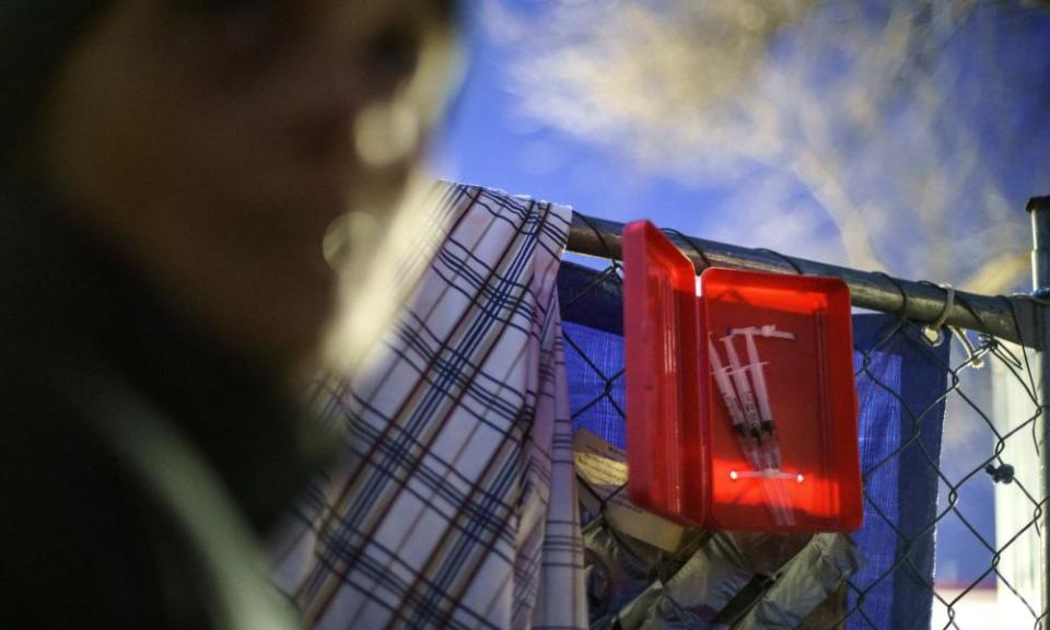 red box filled with syringes attached to a wire mesh fence