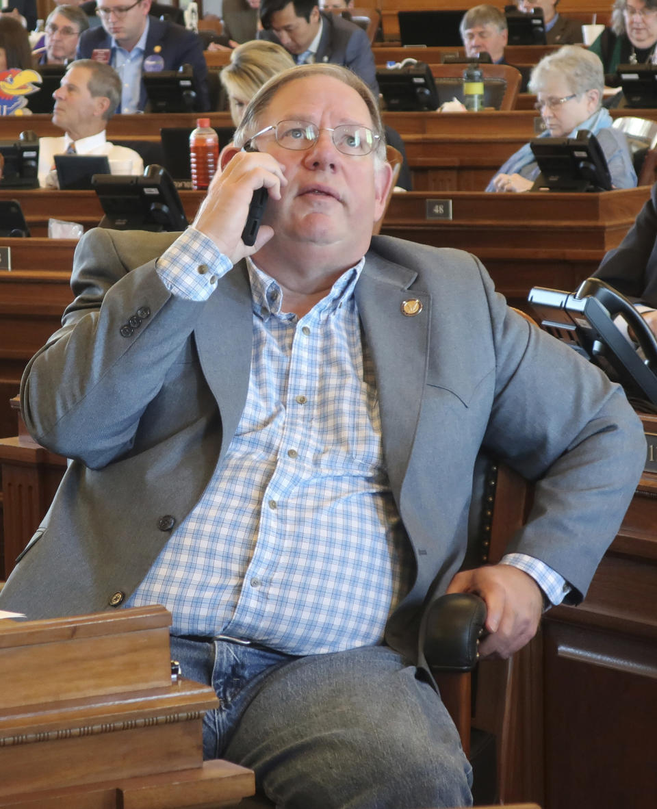 Kansas House Majority Leader Dan Hawkins, R-Wichita, talks on his cell phone and watches a vote-tallying board as the House passes a proposed state budget at the Statehouse Saturday, May 4, 2019, in Topeka, Kan. The budget passed after an effort to block it in hopes of forcing a debate on Medicaid expansion collapsed. (AP Photo/John Hanna)