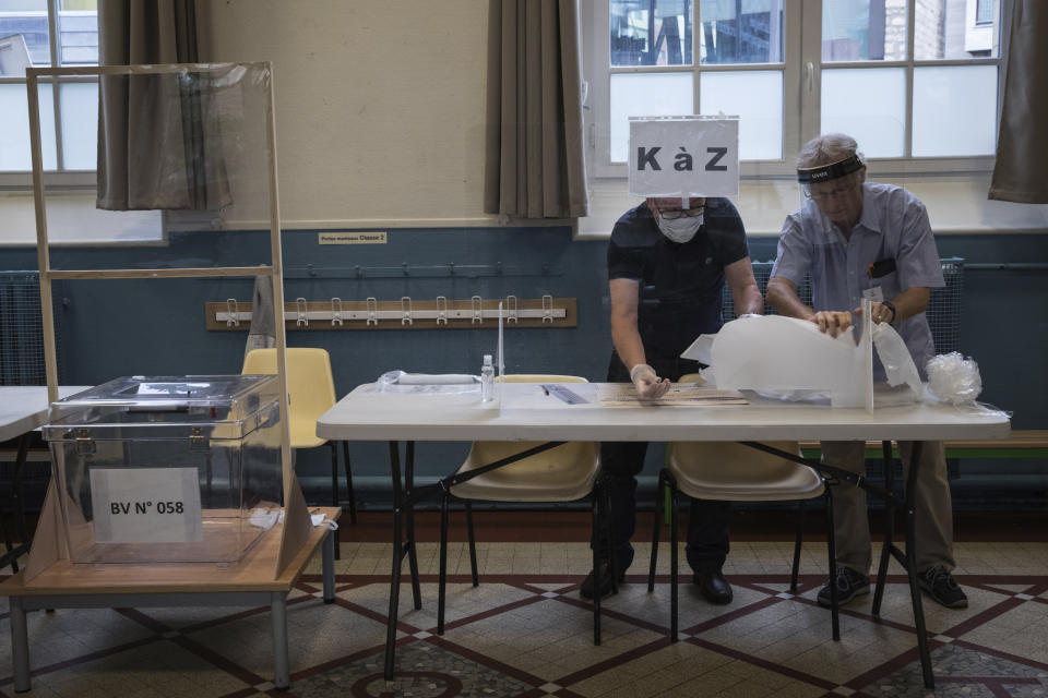 People install plexiglass as part of security measures in a polling station for the second round of the municipal elections, Sunday, June 28, 2020 in Paris. France is holding the second round of municipal elections in 5,000 towns and cities Sunday that got postponed due to the country's coronavirus outbreak. (Joel Saget, Pool via AP)