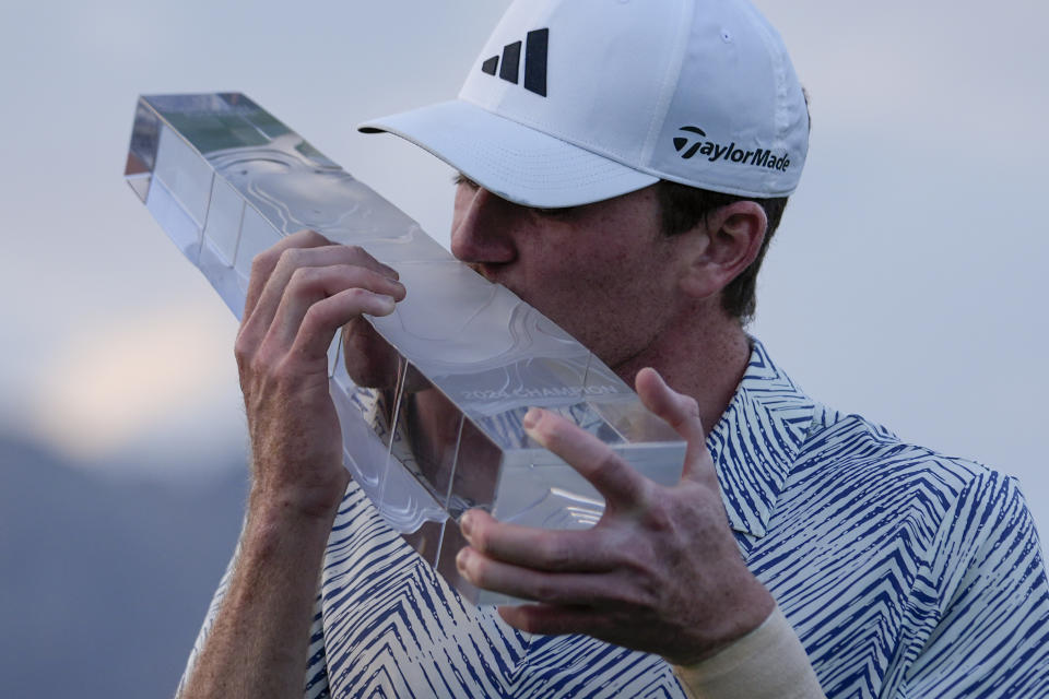 Nick Dunlap kisses the trophy after winning the American Express golf tournament, Sunday, Jan. 21, 2024, in La Quinta, Calif. (AP Photo/Ryan Sun)