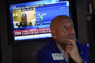 Specialist Meric Greenbaum works at his post on the floor of the New York Stock Exchange, Friday, Aug. 25, 2023, as Federal Reserve Chair Jerome Powell's speech shows on a television screen. Stocks are holding on to gains after Powell said more rate hikes could be on the way to continue the Fed's fight against inflation. (AP Photo/Richard Drew)