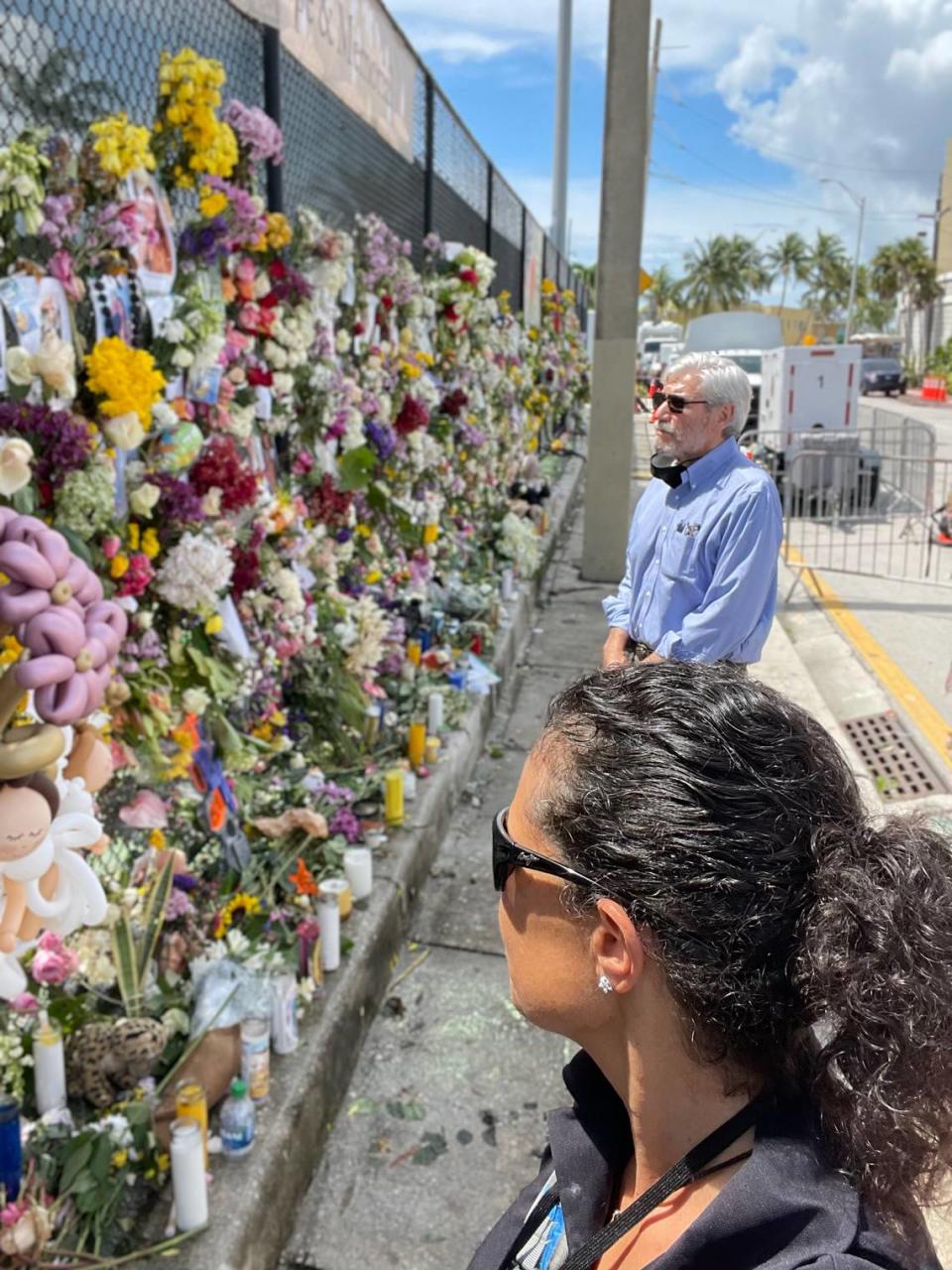 El presidente ejecutivo de la Federación Judía del Gran Miami, Jacob Solomon, al fondo, y Stephanie Viegas de la federación visitan el memorial para las 98 personas que murieron durante el colapso parcial de la torre de condominios Champlain Towers South en Surfside el 24 de junio de 2021.