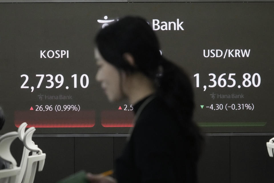 A currency trader passes by the screen showing the Korea Composite Stock Price Index (KOSPI), left, and the foreign exchange rate between U.S. dollar and South Korean won at the foreign exchange dealing room of the KEB Hana Bank headquarters in Seoul, South Korea, Friday, May 10, 2024. (AP Photo/Ahn Young-joon)