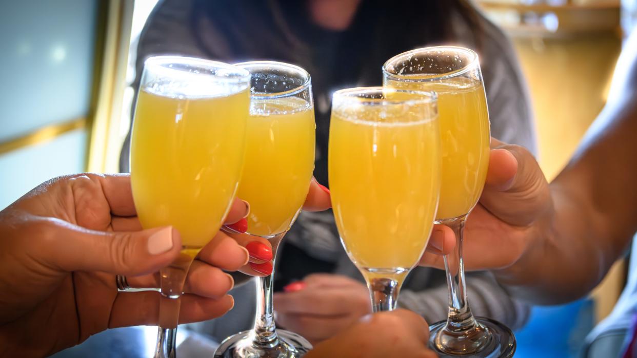 A group of friends share a mimosa toast at brunch.