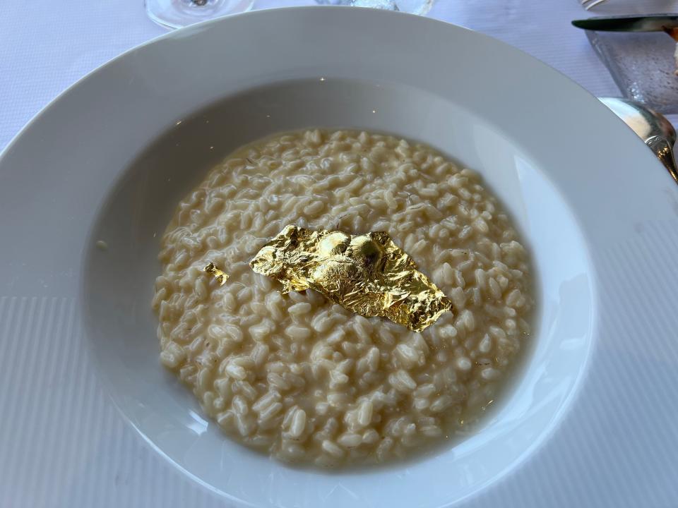 A plate of risotto with a gold leaf on top of it.