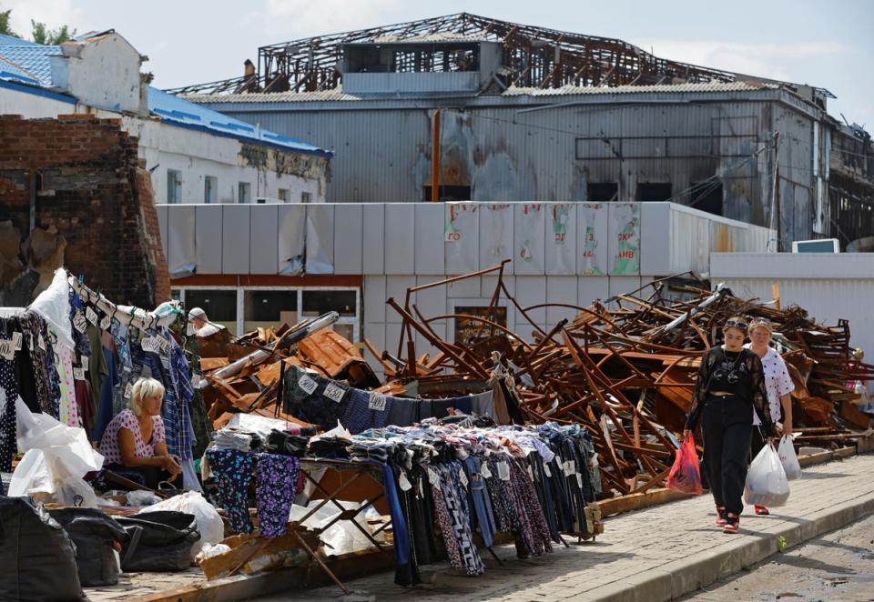 Shoppers continue about their business at a market damaged by airstrikes (Reuters)