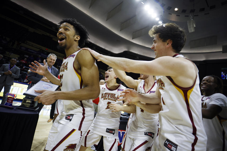 FILE - Loyola's (La.) Zach Wrightsil, left, is congratulated by his teammates after winning the NAIA Player of the Year award as they celebrate their 71-56 win over Talladega in the national championship college basketball game, Tuesday, March 22, 2022, in Kansas City, Mo. They already overcame the ravages of a hurricane to win a national title at their old school. Now former Loyola-New Orleans teammates Zach Wrightsil, Myles Burns and Brandon Davis are aiming for one more improbable achievement as they attempt to make the leap from their NAIA program and succeed at the NCAA Division I level. (AP Photo/Colin E. Braley, File)