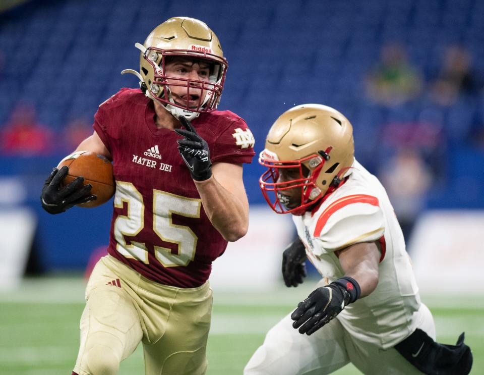 Mater Dei's Joey Pierre (25) runs with the ball as Andrean's Trevon Stephens (2) attempts a tackle during the IHSAA Class 2A football state championship between the Mater Dei Wildcats and the Andrean Fighting 59ers at Lucas Oil Stadium in Indianapolis, Ind., Saturday afternoon, Nov. 27, 2021.