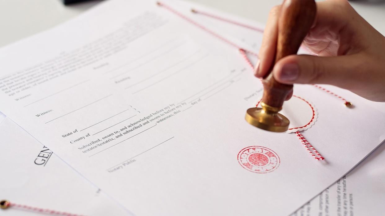 Close up on woman's notary public hand ink stamping the document.