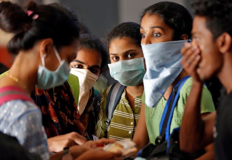 A group of students wearing protective masks wait to buy tickets at a railway station amid coronavirus fears, in Kochi