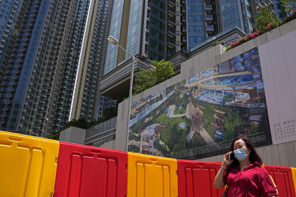 In this Tuesday, June 15, 2021, photo, a woman walks in front of the Grand Central residential building complex where one of the HK$10.8 million (US$1.4 million) 449 square feet single-room flats will be offered as a prize in a lucky draw. Coronavirus vaccine incentives offered by Hong Kong companies, including a lucky draw for an apartment, a Tesla car and even gold bars, are helping boost the city’s sluggish inoculation rate. (AP Photo/Kin Cheung)