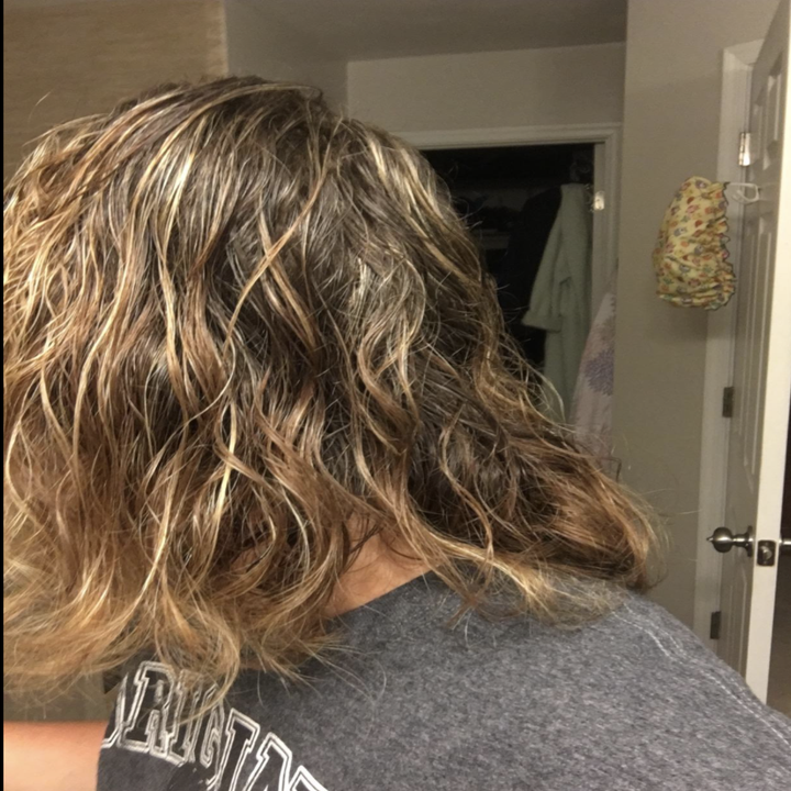 A before photo of a reviewer with her hair wet and curly