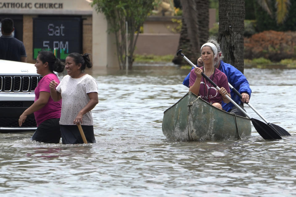 Residents paddle and walk along a flooded road Thursday, April 13, 2023, in Fort Lauderdale, Fla. Over two feet of rain fell causing widespread flooding, closing the Fort Lauderdale airport and turning thoroughfares into rivers. It's been a rainfall tale of two states in Florida this year, where the southeast coast has been inundated by sometimes-record rainfall and much of the Gulf coast is dry as a bone. (AP Photo/Marta Lavandier, File)