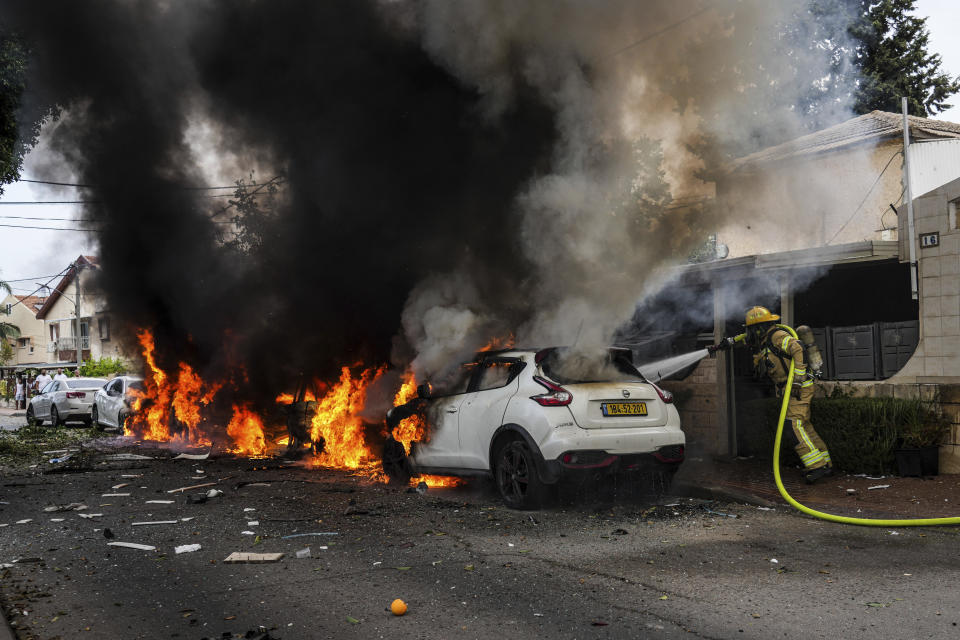 Israeli firefighters extinguish fire at a site struck by a rocket fired from the Gaza Strip, in Ashkelon, southern Israel, Monday, Oct. 9, 2023. (AP Photo/Tsafrir Abayov)