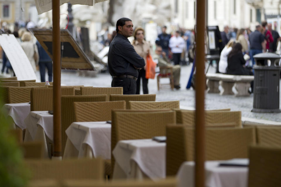 A waiter stands among empty tables in a restaurant in central Rome, Tuesday, April 24, 2012. Both Italy and Spain are struggling to convince markets they can pay their debts despite shrinking economies. Prime ministers Mariano Rajoy in Madrid and Mario Monti in Rome are trying to cut deficits and push through reforms to their countries rules on hiring and firing people to make them more business friendly. (AP Photo/Andrew Medichini)