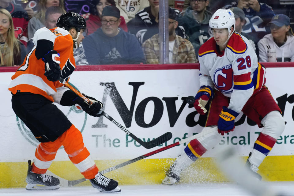 Philadelphia Flyers' Scott Laughton, left, and New Jersey Devils' Damon Severson battle for the puck during the third period of an NHL hockey game, Saturday, Dec. 3, 2022, in Philadelphia. (AP Photo/Matt Slocum)