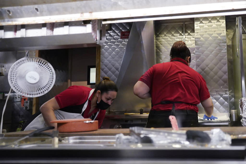 Two women in red shirts working in a kitchen in a restaurant