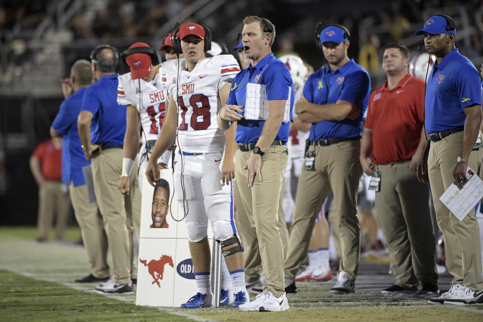 FILE - SMU offensive coordinator Rhett Lashlee, center, calls out instructions from the sideline during the first half of an NCAA college football game against Central Florida Saturday, Oct. 6, 2018, in Orlando, Fla. SMU hired Rhett Lashlee as its new head coach Monday, Mov. 29, 2021, bringing back its former offensive coordinator to replace Sonny Dykes.(AP Photo/Phelan M. Ebenhack, File)