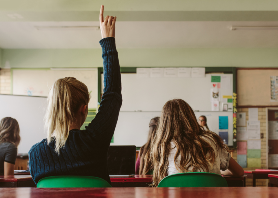 A student raising their hand in class.