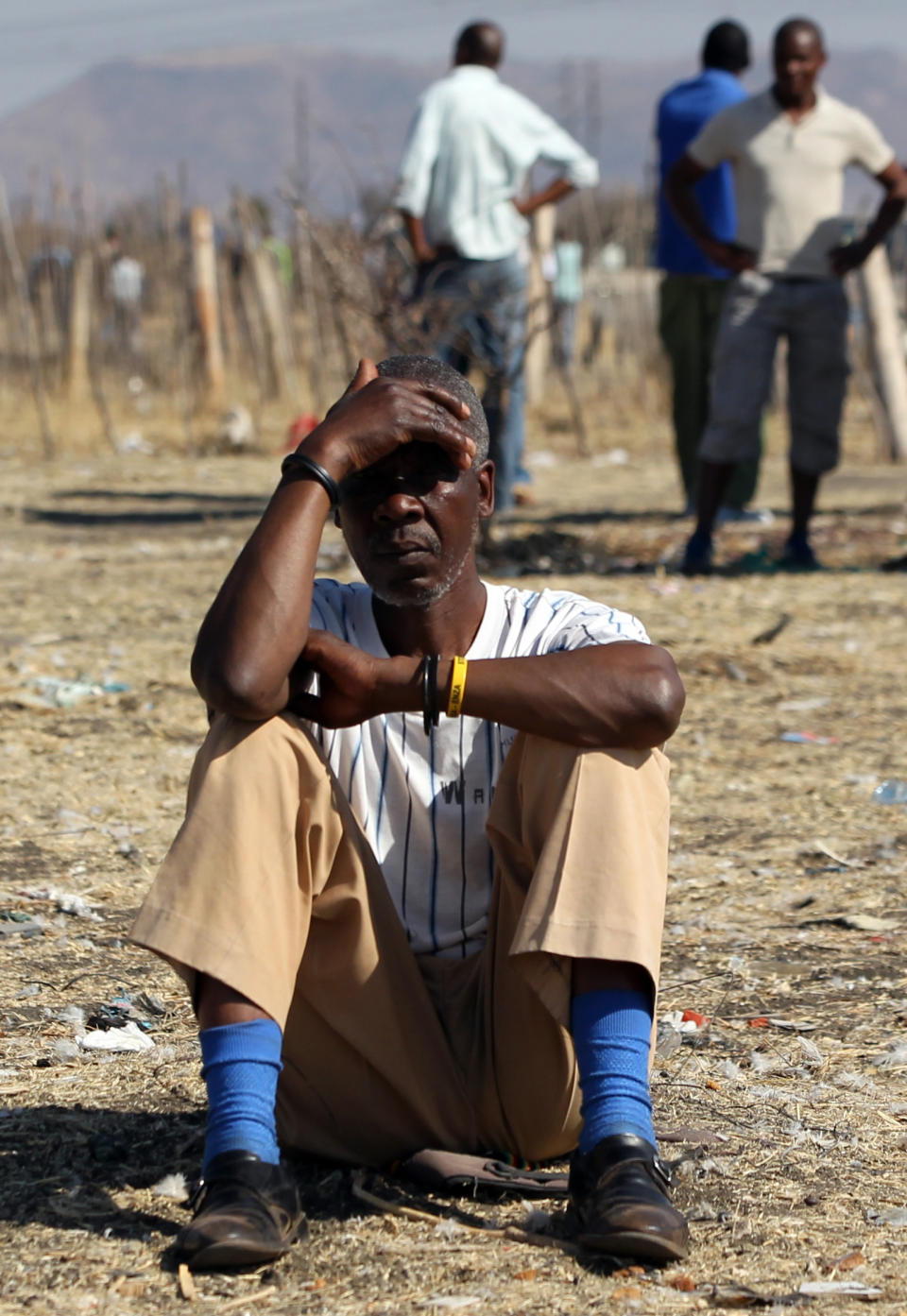 A mine worker Thabo Leribe sits as they wait for a report back from their union at the Lonmin mine near Rustenburg, South Africa, Tuesday, Aug. 21, 2012. Mine Workers trickled in Tuesday at the Lonmin platinum mine where 44-people have died in a wildcat strike, as South Africa urged the company to suspend an ultimatum to return to work. (AP Photo/Themba Hadebe)